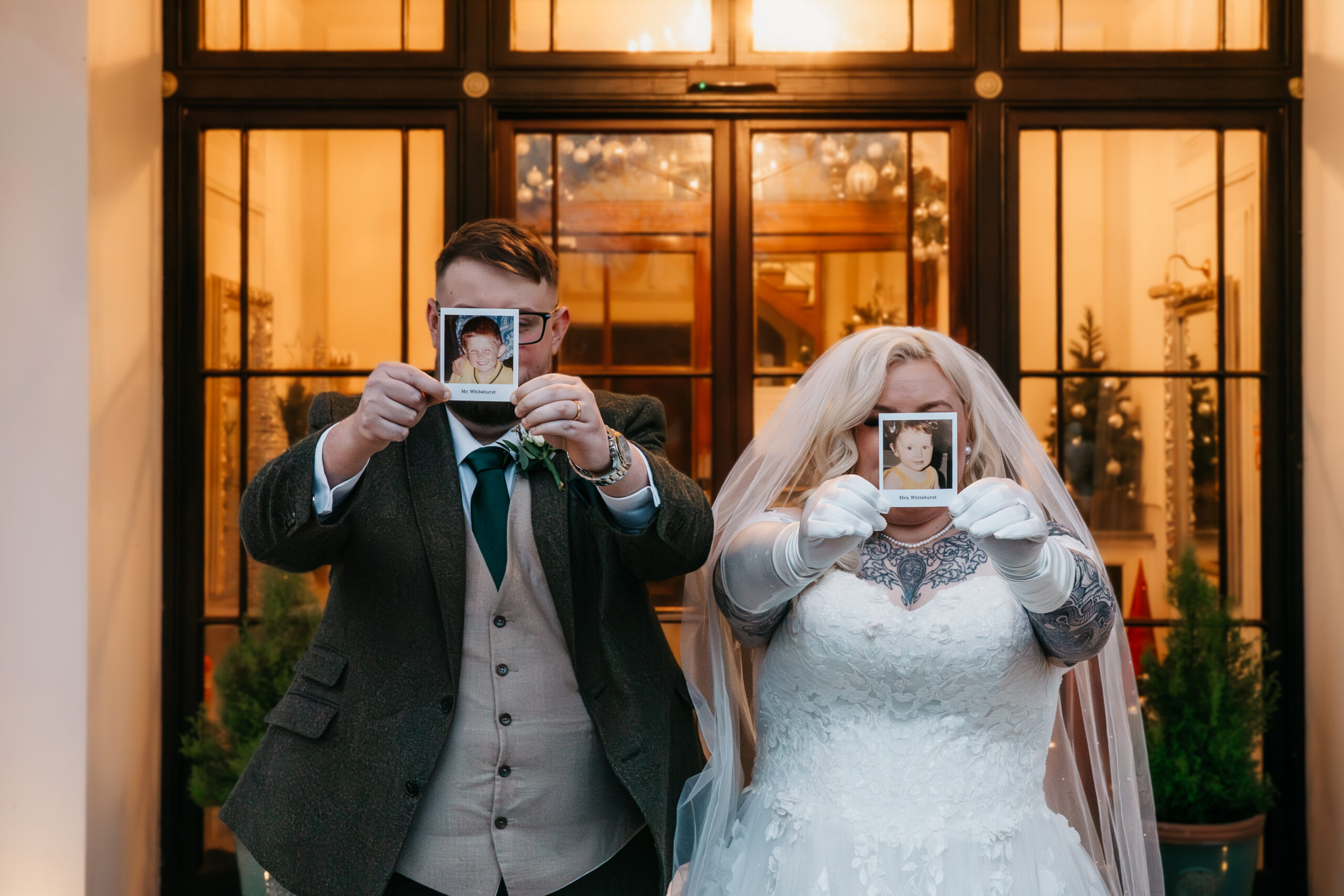 Bride and groom holding childhood photos.