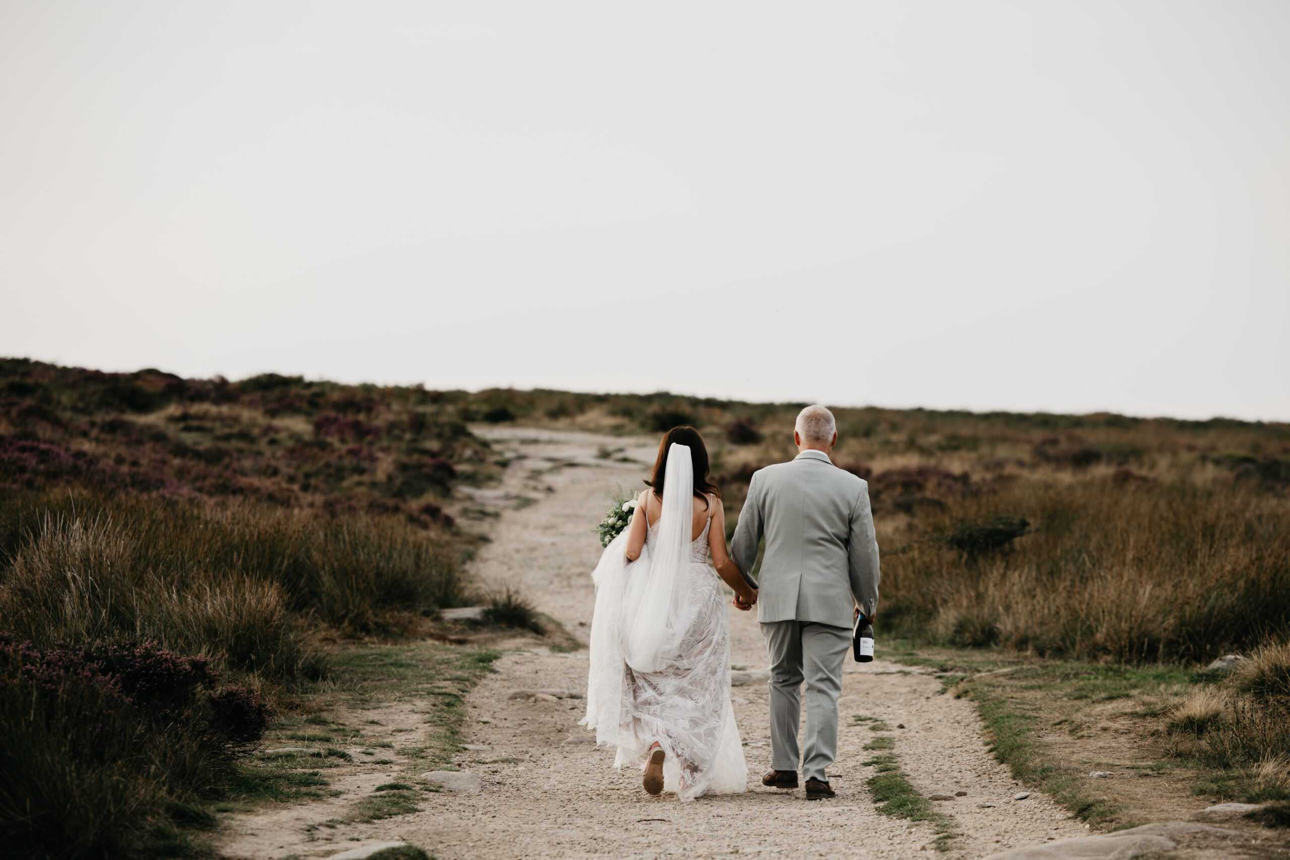 Bride and groom walking on country path together.